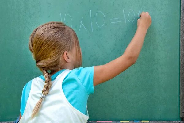在复古绿色黑板上写数学问题的年轻女孩 — 图库照片