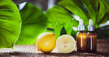 Şişe limon yağı, taze meyve bütün ve yarı tropikal doğal bir arka plan üzerinde.