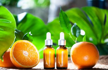 Portakal yağı, taze meyve bütün ve doğal tropikal arka plan üzerinde yarım şişe.