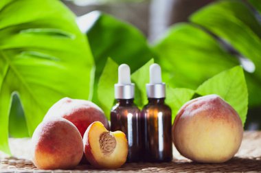 Şeftali yağı, taze Şeftali meyve bütün ve doğal tropikal arka plan üzerinde yarım şişe. Homeopatik ve bitkisel tıp.