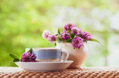 Bir fincan çay güzel yaz bileşimi ve doğal yeşil yonca çiçek arka plan, bir kavramı Günaydın, ruh hali, mutluluk yaz