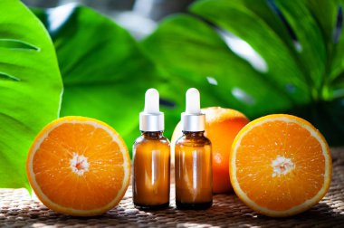 Portakal yağı, taze meyve bütün ve doğal tropikal arka plan üzerinde yarım şişe.