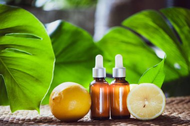 Şişe limon yağı, taze meyve bütün ve yarı tropikal doğal bir arka plan üzerinde.