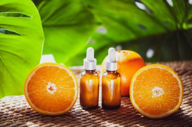 Portakal yağı, taze meyve bütün ve doğal tropikal arka plan üzerinde yarım şişe.