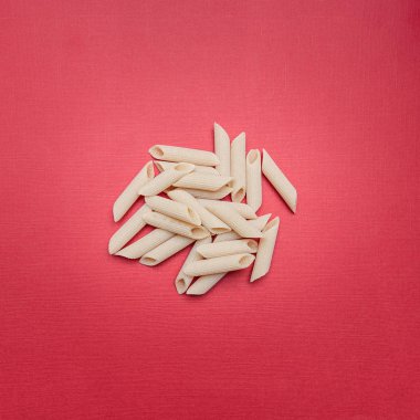 Kuru makarna bir kırmızı arka plan, şık konsept, penne düz yatıyordu