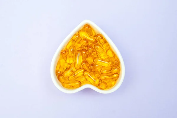 Heart-shape plate with fish oil capsules omega 3, healthy produc — Stock Photo, Image