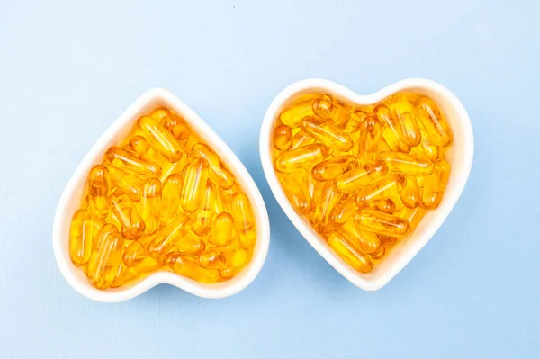 Heart-shape plate with fish oil capsules omega 3, healthy produc — Stock Photo, Image