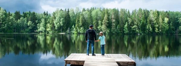 Father with a small daughter are standing on the pier of a beaut