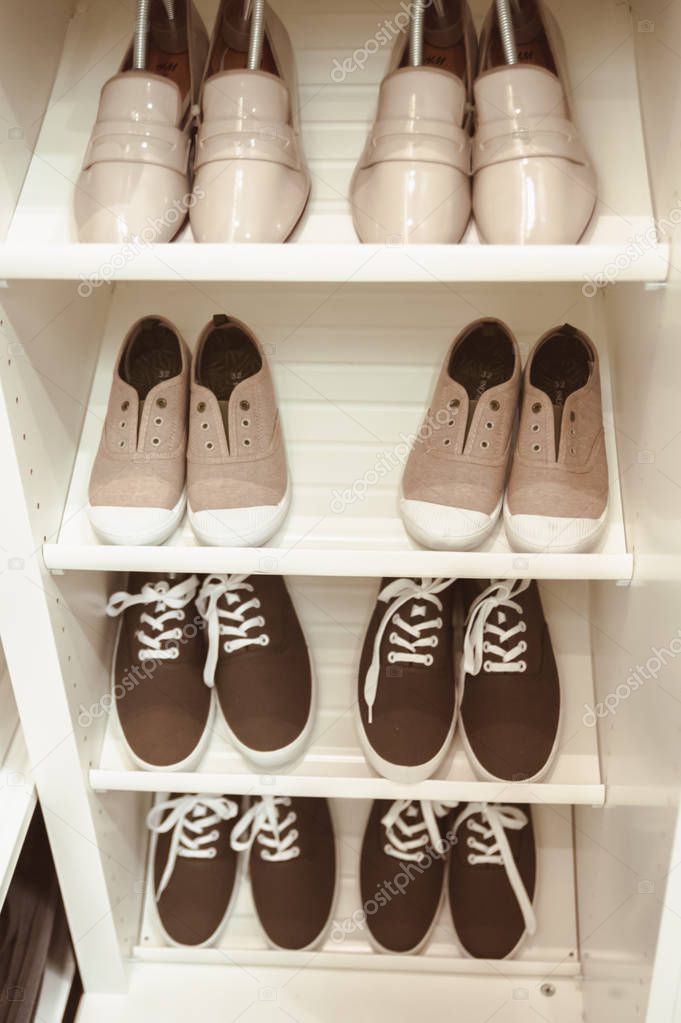 Several pairs of sneakers and other shoes on a shoe shelf, shoe 