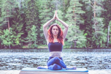 Gölde doğada yoga yapan genç kız. Kadın hap