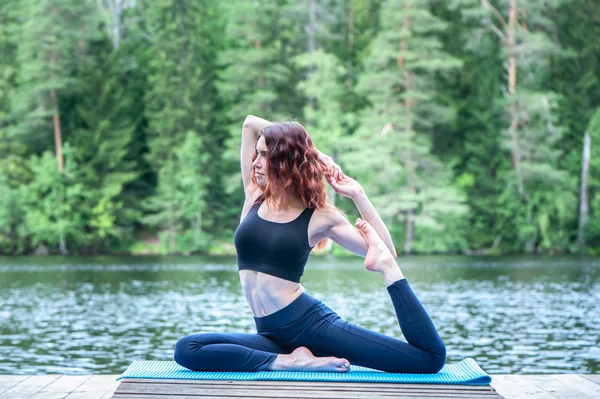 Schöne Mädchen in einer Yoga-Pose am See. eka pada rajakapotasa — Stockfoto