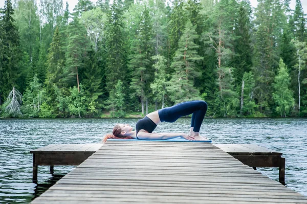 Gölde doğada yoga yapan genç kız. Kadın hap
