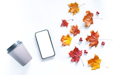 Sonbahar kompozisyonu telefon, kağıt bardak ve sonbahar yaprakları.