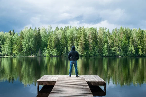 Man stands on the pier of a beautiful lake, panoramic photo. The