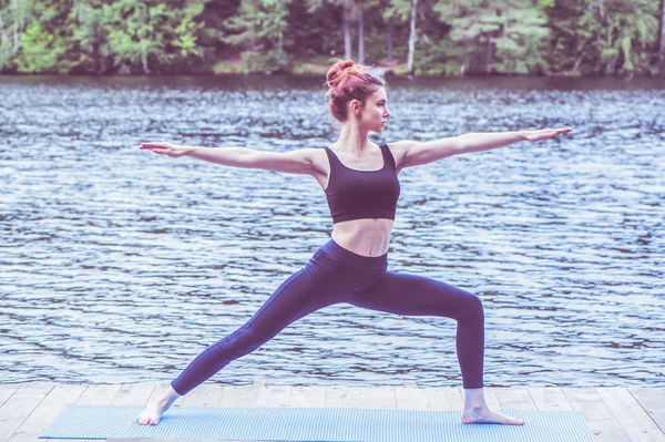 Young yogi  girl  practicing yoga, standing in Warrior two exerc