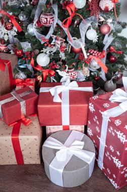 Kutular kırmızı renkli bir Noel ağacının altında kurdelelerle bağlanmış. Sy.