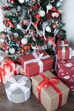 Kutular kırmızı renkli bir Noel ağacının altında kurdelelerle bağlanmış. Sy.