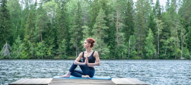 Balıkların yarı lordu Ardha Matsyendrasana gölde namaste ile poz veriyor. Yatıştırma konsepti, sağlıklı yaşam tarzı. Panoramik görünüm