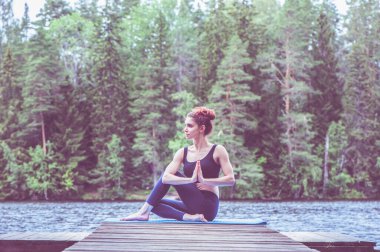Balıkların yarı lordu Ardha Matsyendrasana gölde namaste ile poz veriyor. Uzlaşma kavramı, sağlıklı yaşam tarzı.. 
