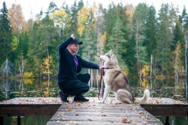 Güz havasında, güzel bir gölün rıhtımında köpekli bir adam. Genç adam doğada bir köpeği eğitiyor.