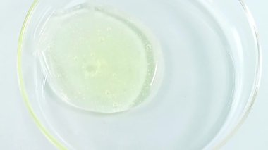 Bir sıvı kozmetik ürünü şeffaf bir laboratuvar cam kavanozuna dökülüyor. 