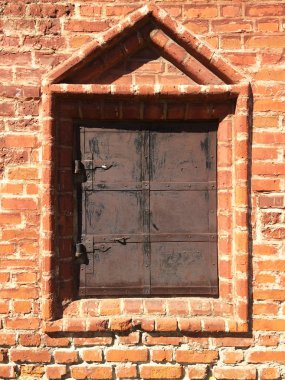 Antik kilise pencere kapalı. Eski metal eski püskü çekim taş çerçeve. Turuncu tuğla duvar eski mimari nesne. Koyu kahverengi sert metal yüzey üzerinde menteşe.