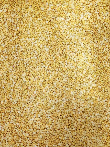 petite yellow mung lentil raw uncooked beans moong dal close up. background texture