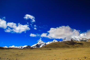 Derin mavi gökyüzü ve buz beyaz bulutlar ile Himalaya Dağları doruklarına gün süre içinde şapkalı.