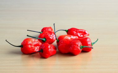 Bunch of Red Bhoot Jolokia Spicy ghost pepper isolated in wooden background with space for text clipart