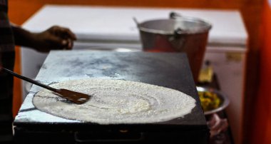 İnce levha üzerinde pirinç ve dal ve yağlama dosa meyilli karışımı yayılan bir Tawa Pan üzerinde kağıt düz dosa yapma