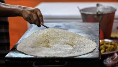 Dosa yağda kızartılır sonra pişirme kaşık ile bir Tawa Pan üzerinde kağıt düz dosa kenarı serbest bırakma.