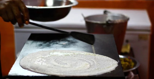 Making of paper plain Dosa on a tawa pan by spreading dosa batter mix of rice and dal and oiling on the thin sheet