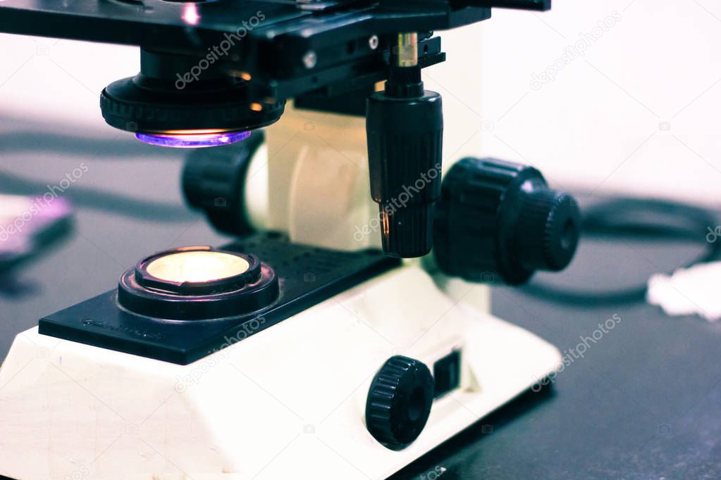 a light microscope with knobs and screws with light on