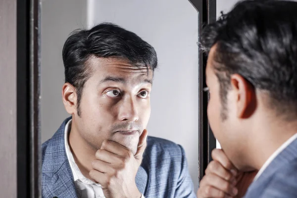 asian man in suit looking after his appearance in front of a mirror beauty styling lifestyle.