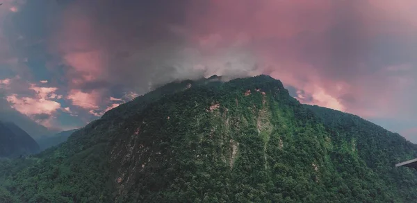 red sky with fog on a mountain top with green vegetation