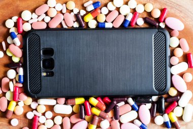 Tıp hapları tablet kapsül hareket eden telefon içinde ahşap arka plan etrafında yığını