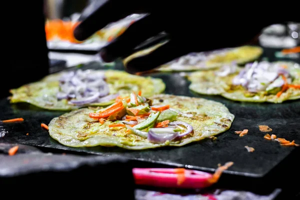 making of egg roll on a hot frying pan with oil and paratha and salad