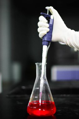 bir otomatik mikro pipet ve mikro ipucu bir kimya laboratuarında bir cam konik şişesi üzerinde kimyasal bir kırmızı aspirating
