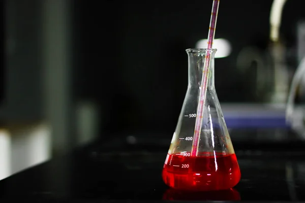 在化学实验室用移液器在玻璃锥形烧瓶上吸气一种红色化学物质 — 图库照片