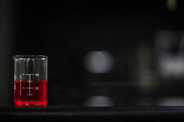 bir cam ölçek koyu arka plan siyah granit tabloda kırmızı sıvı