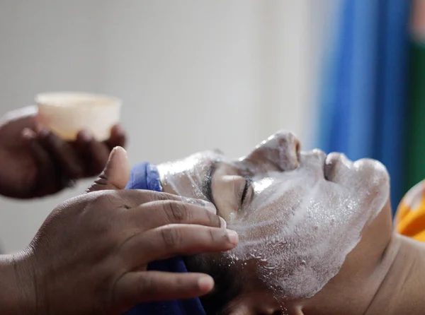 applying facial pack mask on face of a lady with hair band with eyes closed.side view