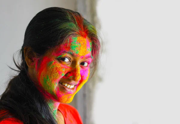 portrait of indian young girl face painted with colors smiling with eyes open with space for text