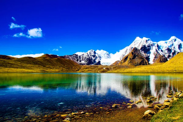 Hala mavi suları üzerinde yansıtan mavi gökyüzü ile ake kıyısında çakıl taşları. doğal Himalaya manzara — Stok fotoğraf