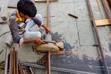 Ağustos 2018,Kalküta, Hindistan, Motorlu Bosch Çelik Çubuk Kesici ile çelik çubuğu kesen ve kıvılcım üreten bir erkek işçi