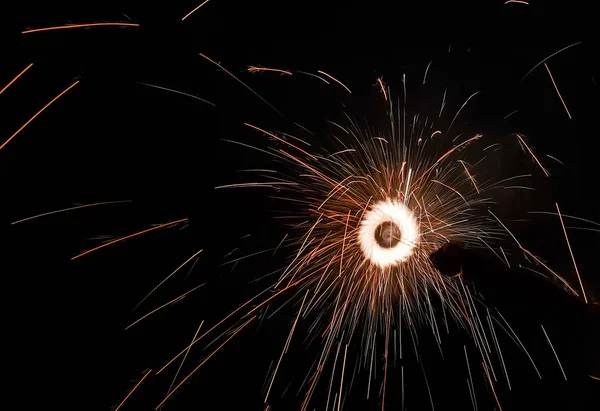 Mano charki, un fuoco d'artificio a mano che emette scintille circolari in sfondo nero — Foto Stock