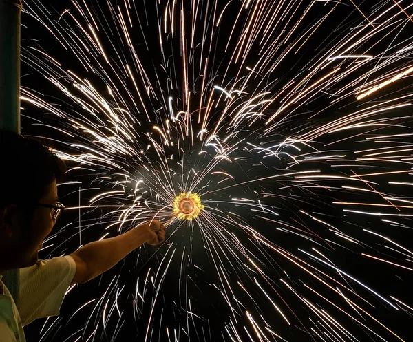 Un uomo che tiene per mano charki, un fuoco d'artificio a mano che emette scintille circolari su sfondo nero — Foto Stock