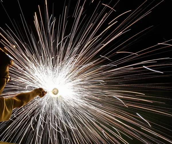 Un uomo che tiene per mano charki, un fuoco d'artificio a mano che emette scintille circolari su sfondo nero — Foto Stock