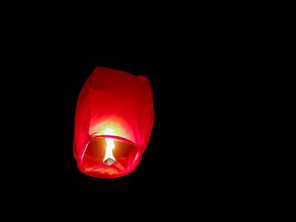 Illuminazione lanterna cielo da un paio di mani che tengono la mongolfiera di carta in uno sfondo nero — Foto Stock