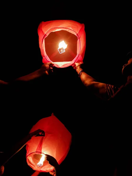 Illuminazione lanterna cielo da un paio di mani che tengono la carta calda ai — Foto Stock