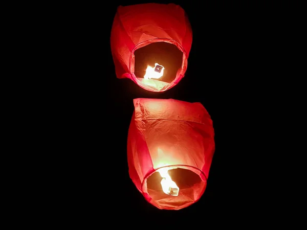 Éclairage lanterne ciel par une paire de mains tenant le ballon d'air chaud en papier dans un fond noir — Photo